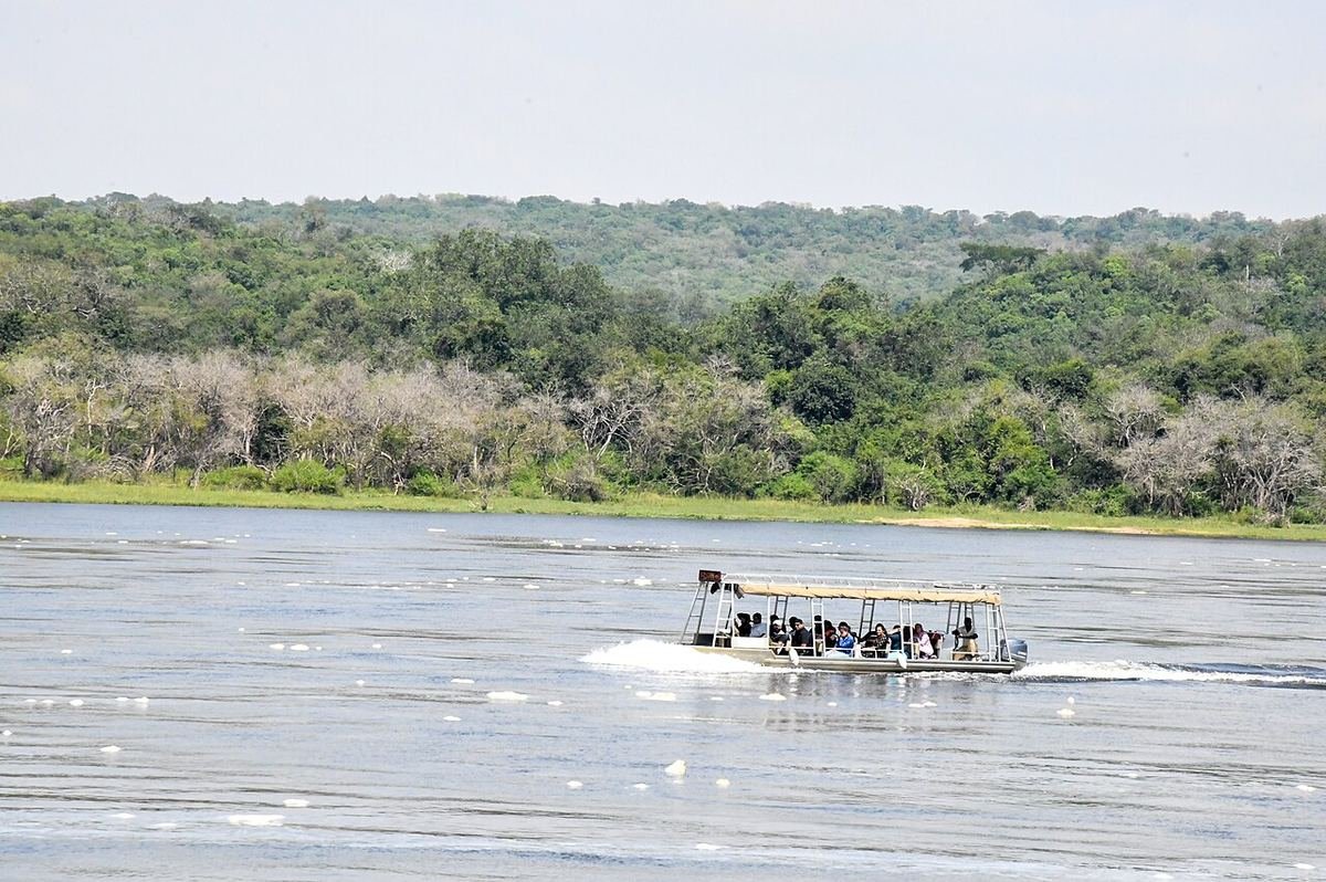 A tourist launch boat on the Nile in Murchison Falls National Park, with forested banks behind