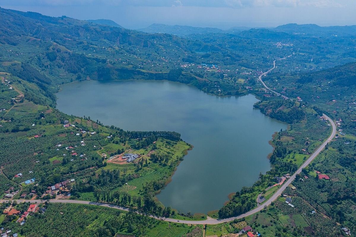 Aerial view of Lake Nkugute, a crater lake in Rubirizi, with a road curving around its shore