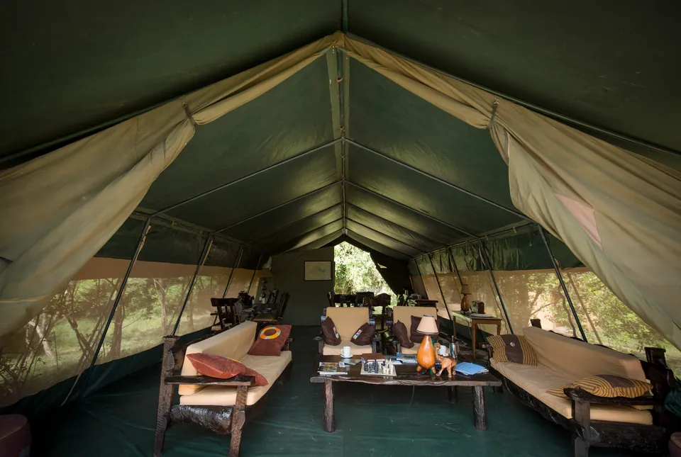 Inside a large safari tent with sofas, a coffee table and a writing desk